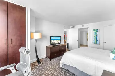 a hotel room with a bed and a flat screen tv at Eternal Sunrise Suite in Fort Lauderdale