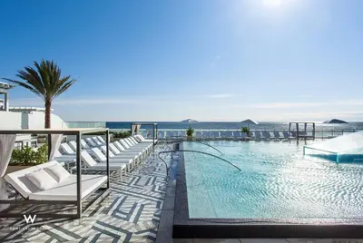 a swimming pool with white lounge chairs and the ocean at 1 Bedroom with ocean and city views! in Fort Lauderdale