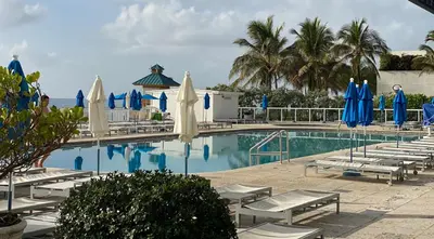 a swimming pool with blue and white umbrellas and chairs at Beachfront condo in Miami! in Sunny Isles Beach