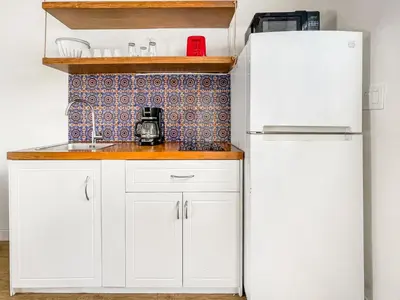 a kitchen with white cabinets and a white refrigerator at Ocean Sound's Hotel in Hollywood