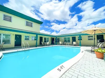 a pool with chairs and umbrellas next to a building at The Delmar in Hollywood