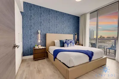 a bedroom with a bed with a blue accent wall at Exclusive Apartment - Rooftop Pool - Hollywood Beach in Hollywood