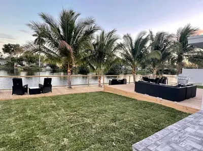 a lawn with chairs and palm trees next to a body of water at 5-star Lakefront Oasis In Hollywood-Hard rock casino in Fort Lauderdale