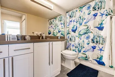 a bathroom with a toilet and a blue and white shower curtain at Uhost AI - 3BR Condo - Stunning Water Views in Miami