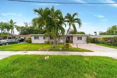 a house with palm trees in front of a driveway at Pool House on the Water 2 in Miami