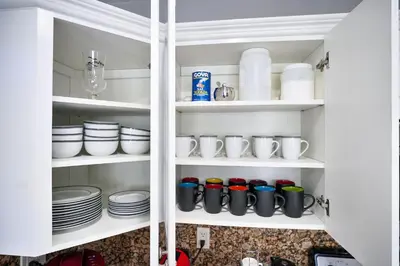a white cabinet with dishes and cups and plates at Vacay Spot Happy Escape 15 Min Beach Massage Shower Prime LOC! 6 blocks away from Bars, Nite Clubs, Res, Shops in Miami