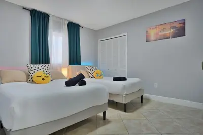two beds in a room with green curtains at Vacay Spot Gables 4 to 23 Guest GameRoom 2 Kitchens 2 BBQ, 2 BAR, Backyard, Patio, Prime LOC! 6 blocks away from Bars, Nite Clubs, Res, Shops in Miami