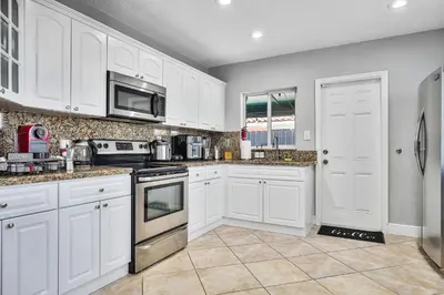 a kitchen with white cabinets and stainless steel appliances at Vacay Spot Gables 4 to 23 Guest GameRoom 2 Kitchens 2 BBQ, 2 BAR, Backyard, Patio, Prime LOC! 6 blocks away from Bars, Nite Clubs, Res, Shops in Miami