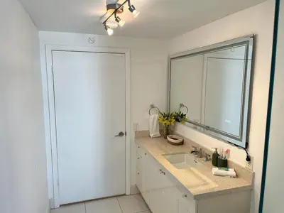 a white bathroom with a sink and a mirror at Direct Ocean View - Luxurious condo in South Beach in Miami Beach