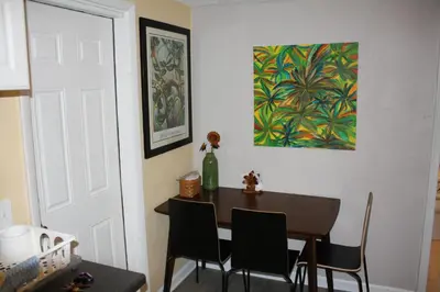 a dining room table with chairs and a painting on the wall at Key West Style Historic Home in Coconut Grove Florida The Yellow House in Miami