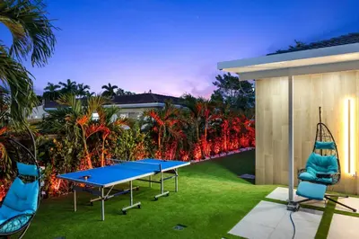 a ping pong table and chairs on a lawn at VillaLee-Jungle Palm Island white marble pool Area in Miami