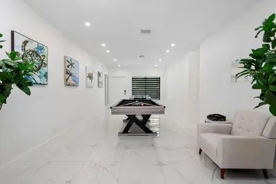 a white room with a table and a couch and paintings at VillaLee-Jungle Palm Island white marble pool Area in Miami