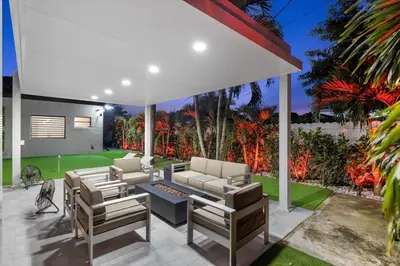 a patio with chairs and a couch and a table at VillaLee-Jungle Palm Island white marble pool Area in Miami