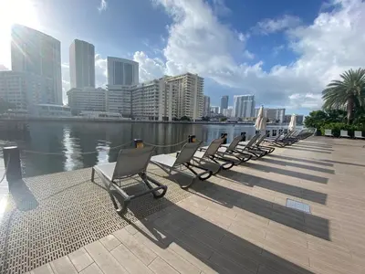 a row of chairs sitting on a pier next to the water at Relaxing BeachWalk Getaway Studio for 4 Guests 405B in Hallandale Beach