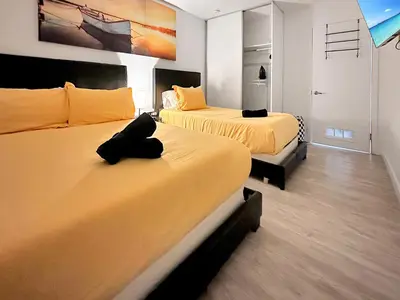 two beds in a room with yellow sheets at Vacay Spot experience Luna Sky! 65