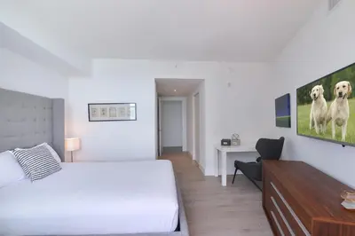 a white bedroom with a bed and a desk at Zen Direct Ocean Front Deluxe 3-Bedroom in Hollywood