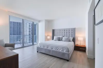 a white bedroom with a bed and a large window at Zen Direct Ocean Front Deluxe 3-Bedroom in Hollywood