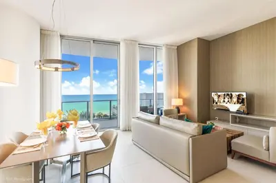 a living room with a table and a dining room with a view of the ocean at Zen Vacation Rentals Direct Ocean Front Low Floor in Hollywood