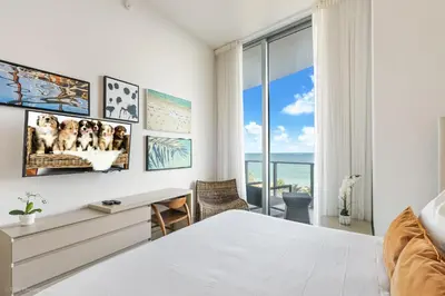 a bedroom with a bed and a desk and a window at Zen Vacation Rentals Direct Ocean Front Low Floor in Hollywood