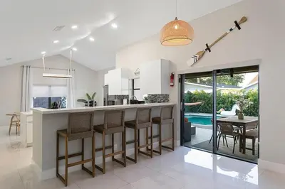 a kitchen with a bar with chairs and a table at Citrus+Sunshine/Heated Pool/6 min to Beach/Casino in Dania Beach