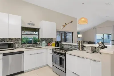 a large white kitchen with white cabinets and appliances at Citrus+Sunshine/Heated Pool/6 min to Beach/Casino in Dania Beach