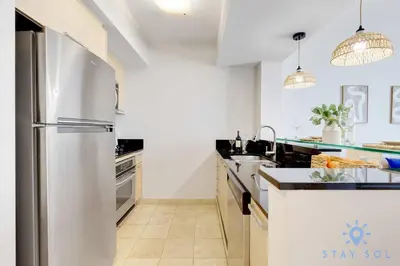 a white kitchen with a stainless steel refrigerator at Beachfront Resort - Pool - Ocean View Balcony- Gym in Miami Beach