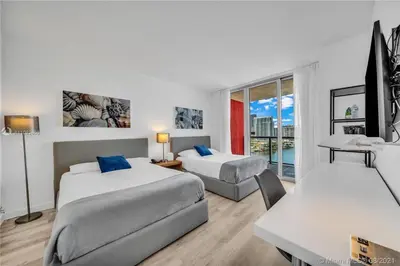 a hotel room with two beds and a table and a desk at BeachWalk Studio Steps from the Sand 2 Full Beds 805 B in Hallandale Beach