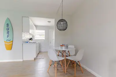 a dining room with a table and chairs and a surfboard at Luxury House with Delightful Beach Style! in Dania Beach