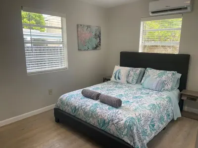 a bedroom with a bed with a comforter and two windows at Luxury House with Delightful Beach Style! in Dania Beach