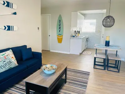 a living room with a blue couch and a surfboard on the wall at Luxury House with Delightful Beach Style! in Dania Beach