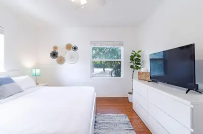 a white bedroom with a tv on a white dresser at The Blue Parrot in Fort Lauderdale