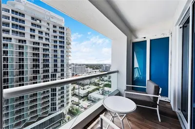 a balcony with a table and chairs and a large window at Luxury Suite at Fort Lauderdale in Fort Lauderdale