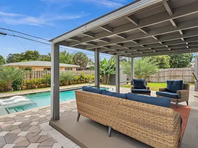 a pergola over a patio with chairs and a pool at Walk 2 Wilton! Heatd Pool & 10 min to Bch Las Olas in Fort Lauderdale