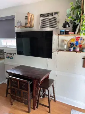 a television hanging on a wall with a table and a stool at The Cozy Villa-private parking in Miami