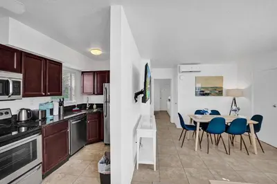 a kitchen with a table and blue chairs in it at Waves On Desoto Rental Unit With Pool in Hollywood