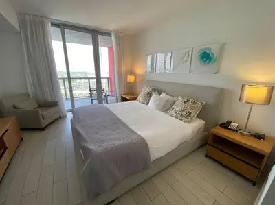 a bedroom with a large bed and a balcony at Elegant Miami Beach Apt Ocean Views, Full Kitchen & Style in Hallandale Beach