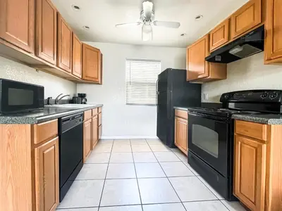 a kitchen with black appliances and wooden cabinets at The Starfish in Hollywood