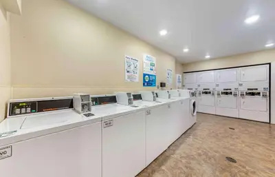 a laundry room with white washing machines and cabinets at Extended Stay America Select Suites - Fort Lauderdale - Airport - West in Davie