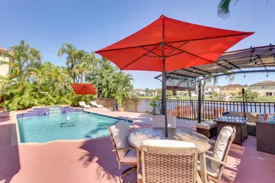 a table with a red umbrella next to a pool at Spacious Miami Retreat with Grill, Pool and Dock! in Miami