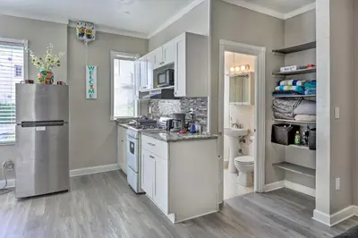 a kitchen with white cabinets and a stainless steel refrigerator at Sunny Miami Beach Condo Steps to Boardwalk! in Miami Beach