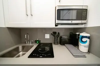 a kitchen counter with a sink and a microwave at Beach Bae -Deco Studio Steps from the Ocean in Miami Beach