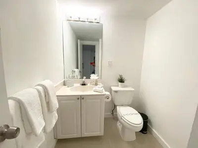 a white bathroom with a toilet and a sink at Zen Vacation Rentals Modern Penthouse Across Ocean in Miami Beach