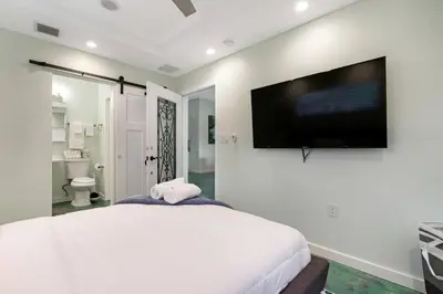 a bedroom with a large white bed and a flat screen tv at Heated Pool I Soundproof Home I Firepit I 630Mbps in Hollywood