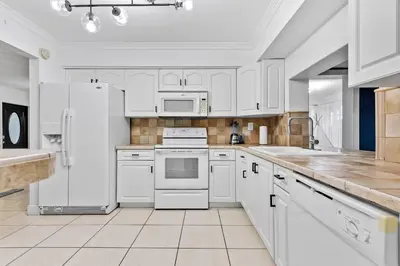 a large white kitchen with white appliances and a counter at Private Lakefront Home in Miami/Pembroke in Pembroke Pines