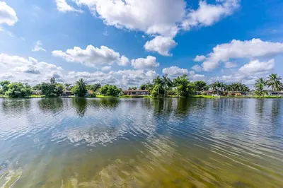 a large body of water with trees and clouds in the sky at Private Lakefront Home in Miami/Pembroke in Pembroke Pines