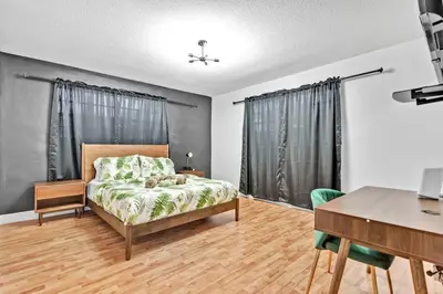 a bedroom with a bed and a table and a desk at Private Lakefront Home in Miami/Pembroke in Pembroke Pines