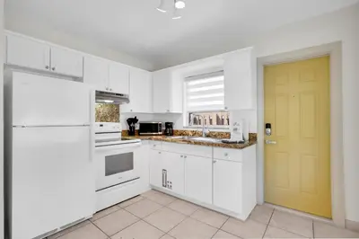 a kitchen with white cabinets and a yellow door at LoKal Rental Tropical Florida destination in Fort Lauderdale