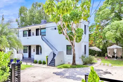 a white house with a tree in front of it at 3 Seasons at the Carrington 3 Two Bedroom 1 Bath Apts -6 Bedrooms 3 bathrooms and 3 bedroom 2 bathroom Villa in Miami