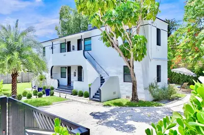 a white house with a tree in front of it at 3 Seasons at the Carrington 3 Two Bedroom 1 Bath Apts -6 Bedrooms 3 bathrooms and 3 bedroom 2 bathroom Villa in Miami