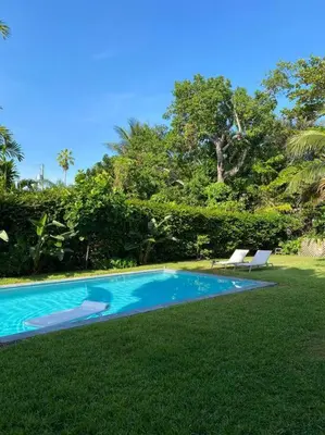 a swimming pool with two lounge chairs in the grass at Miami guest house with large pool in Miami